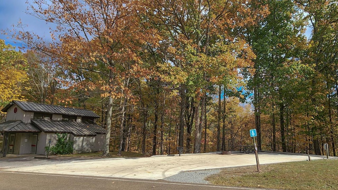 Small building surrounded by autumn trees under a clear blue sky.