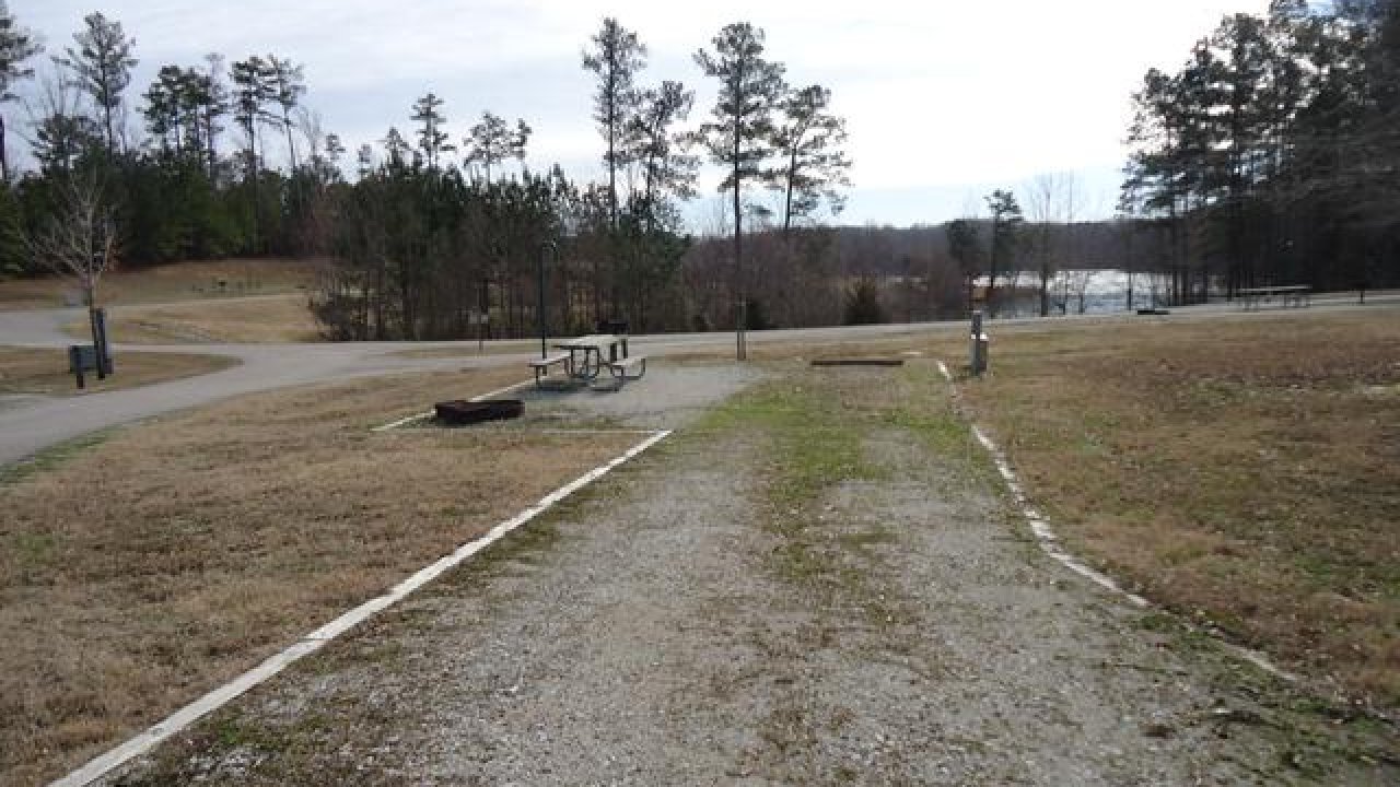 Gravel road in a campground with trees and a picnic table.