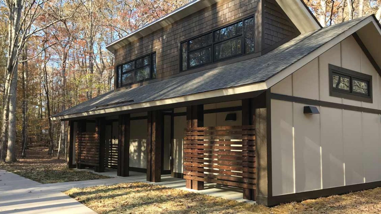 Modern house in a forested area with large windows and wood accents.