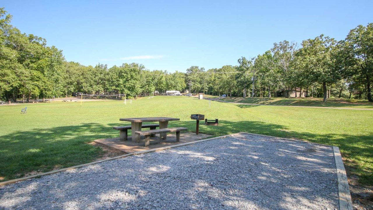 Picnic table in a sunny park with green grass and trees.