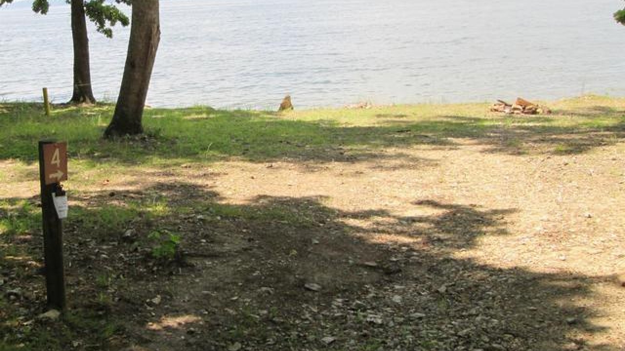 Grassy campsite near a lake, numbered post on the left.