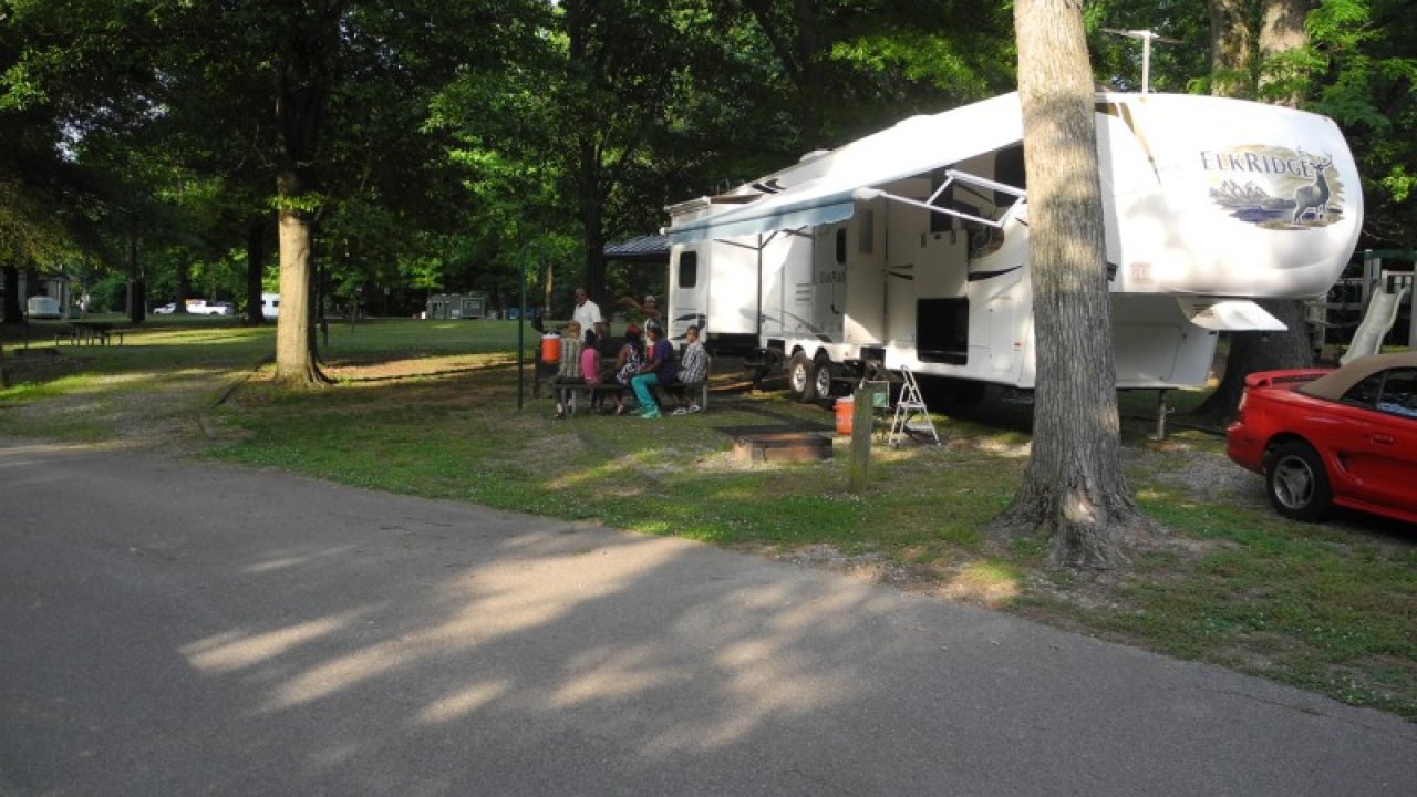 Family camping with their RV in a shaded park area.