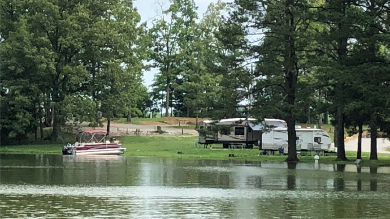 Recreational vehicles by a flooded campground with submerged picnic table.