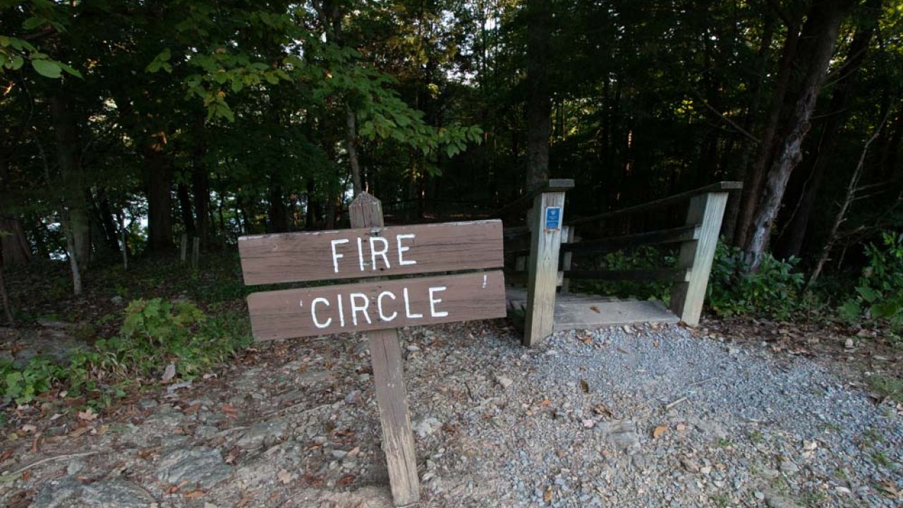 Wooden sign labeled "FIRE CIRCLE" at the start of a forest path.