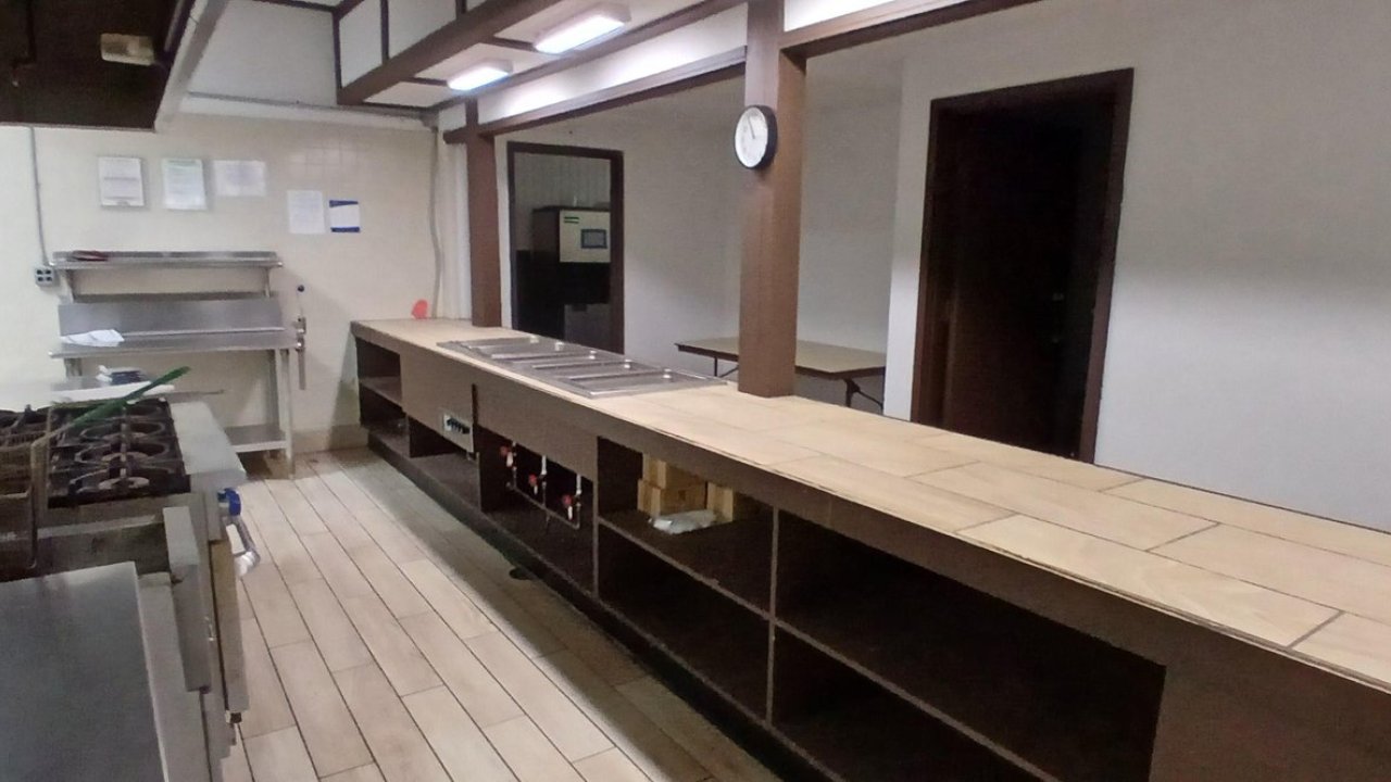 Commercial kitchen with stainless steel appliances and a long wooden counter.