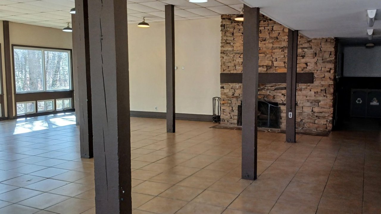 Spacious hall with stone fireplace, tiled floor, and large windows.