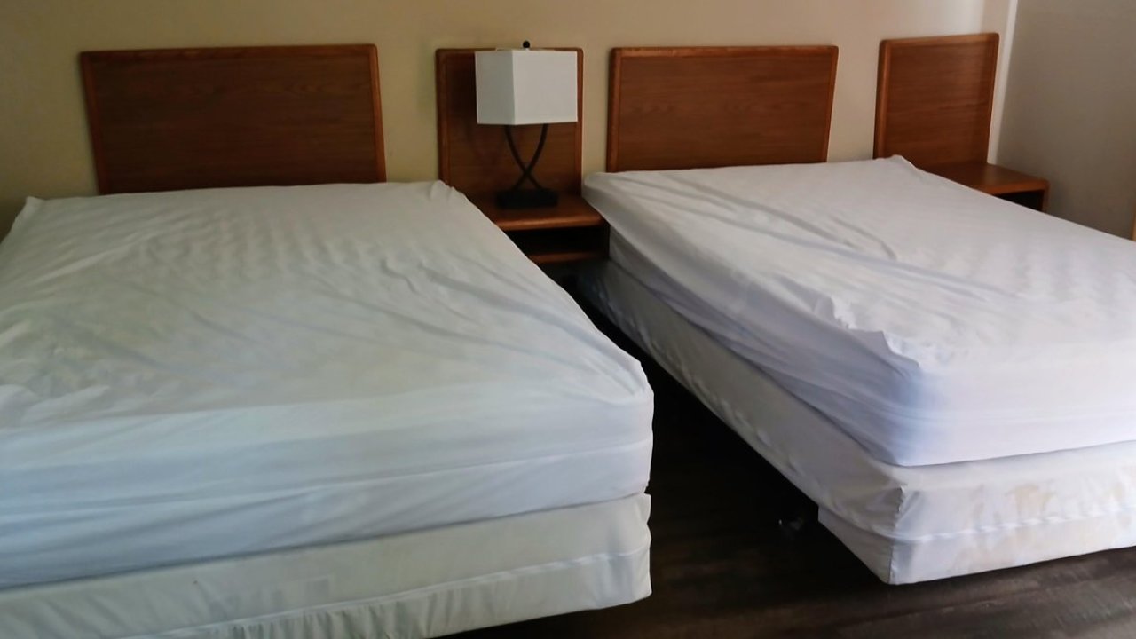 Two twin beds with white sheets in a hotel room.