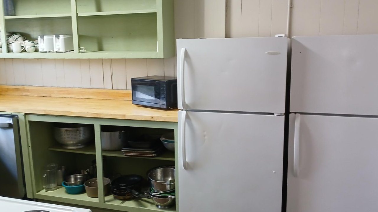 Kitchen with two fridges, a microwave, and open shelves.