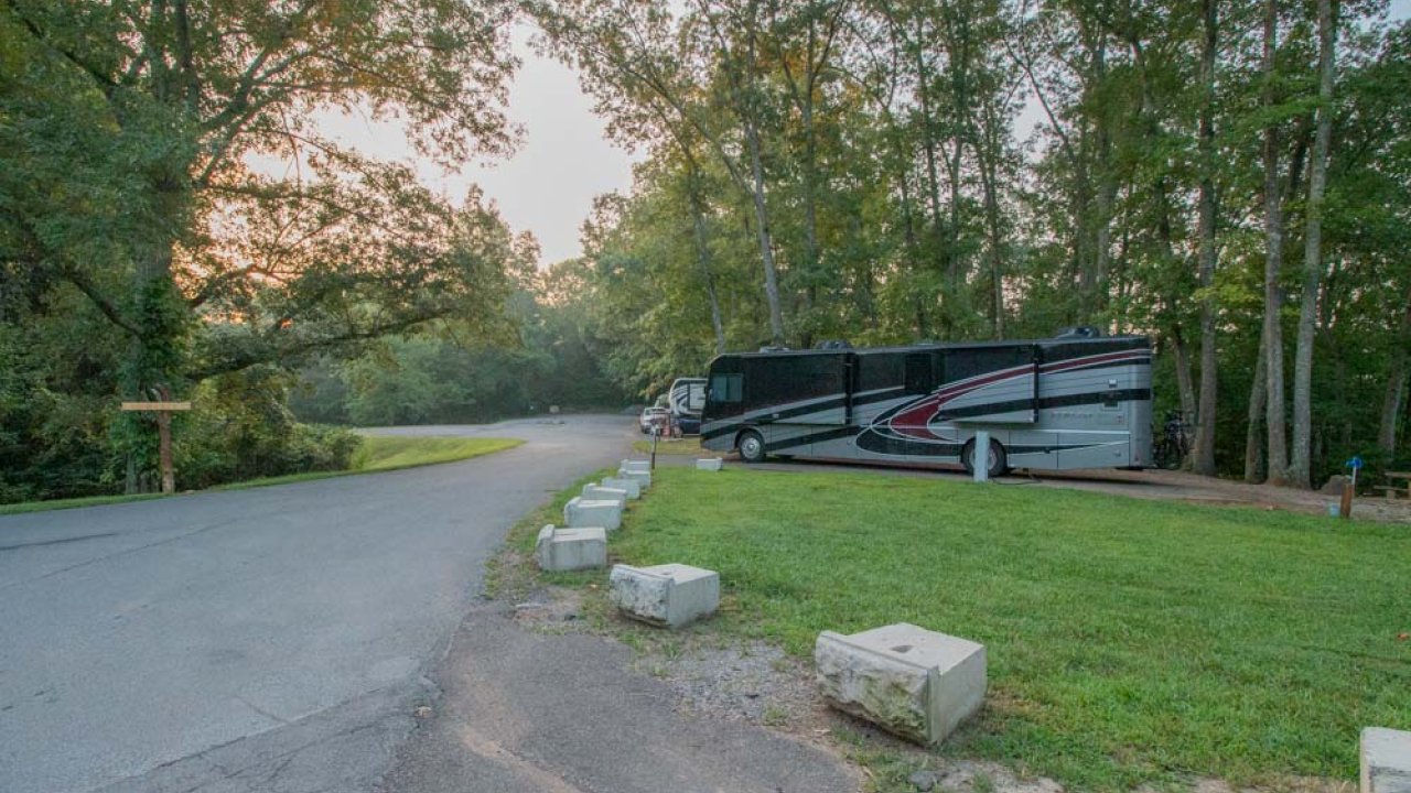 Curved road in a park with canoes stacked on the side at dusk.