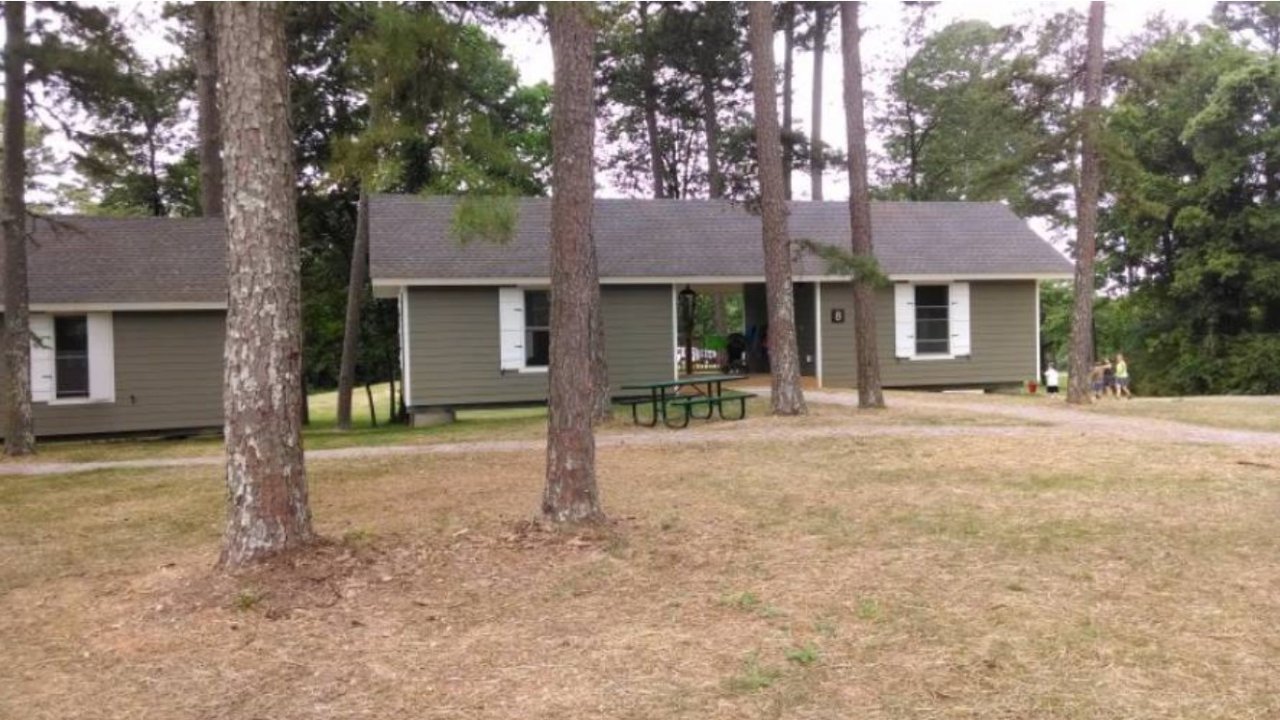 Cabin surrounded by trees and grass in a park setting.