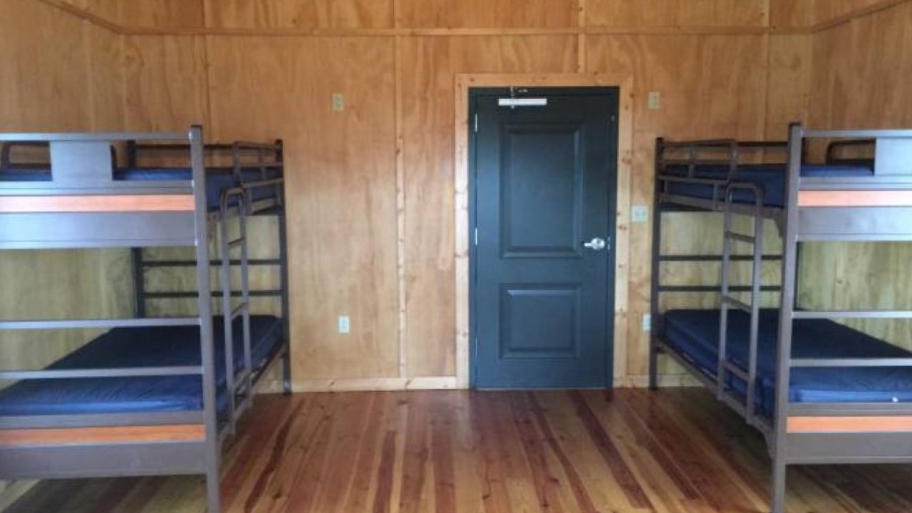 Two bunk beds in a wooden cabin with a closed black door.