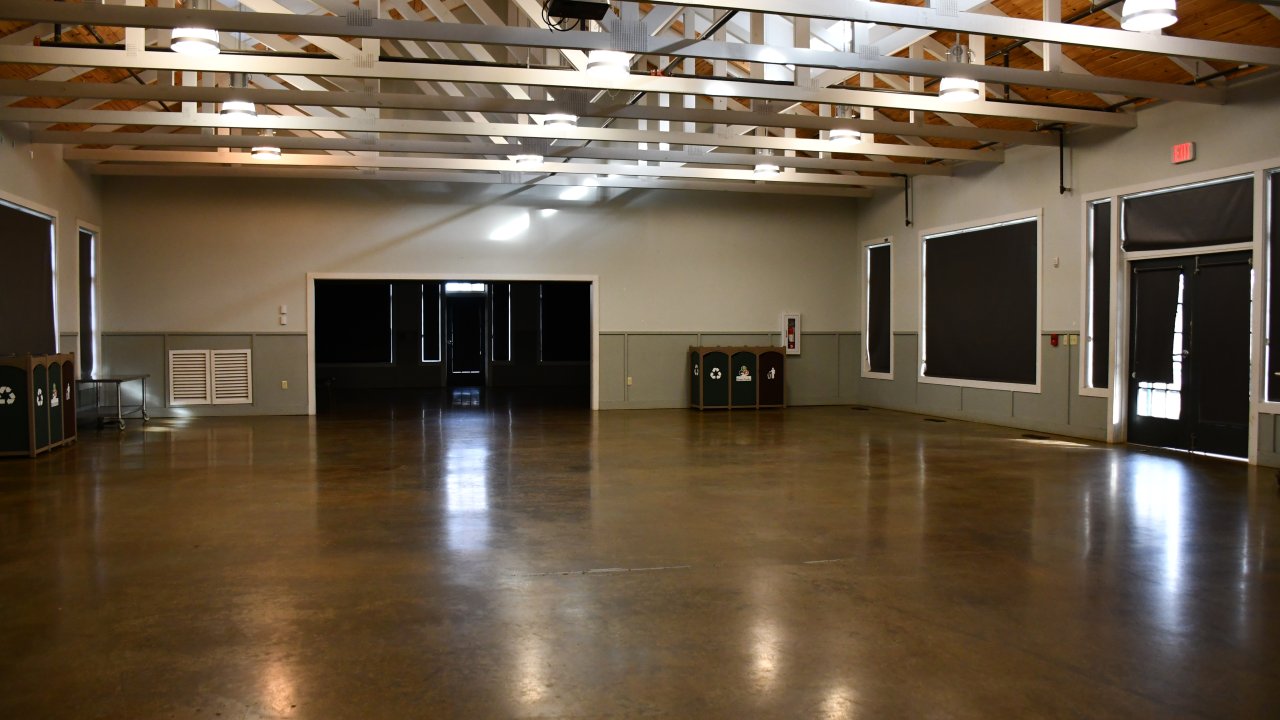Large, empty hall with polished floor and exposed beam ceiling.