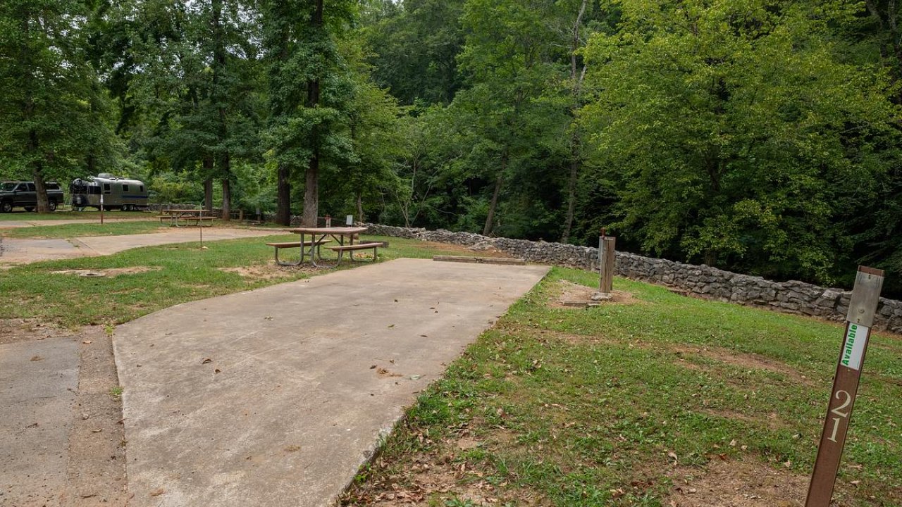 Concrete campsite with picnic table, surrounded by lush green trees.