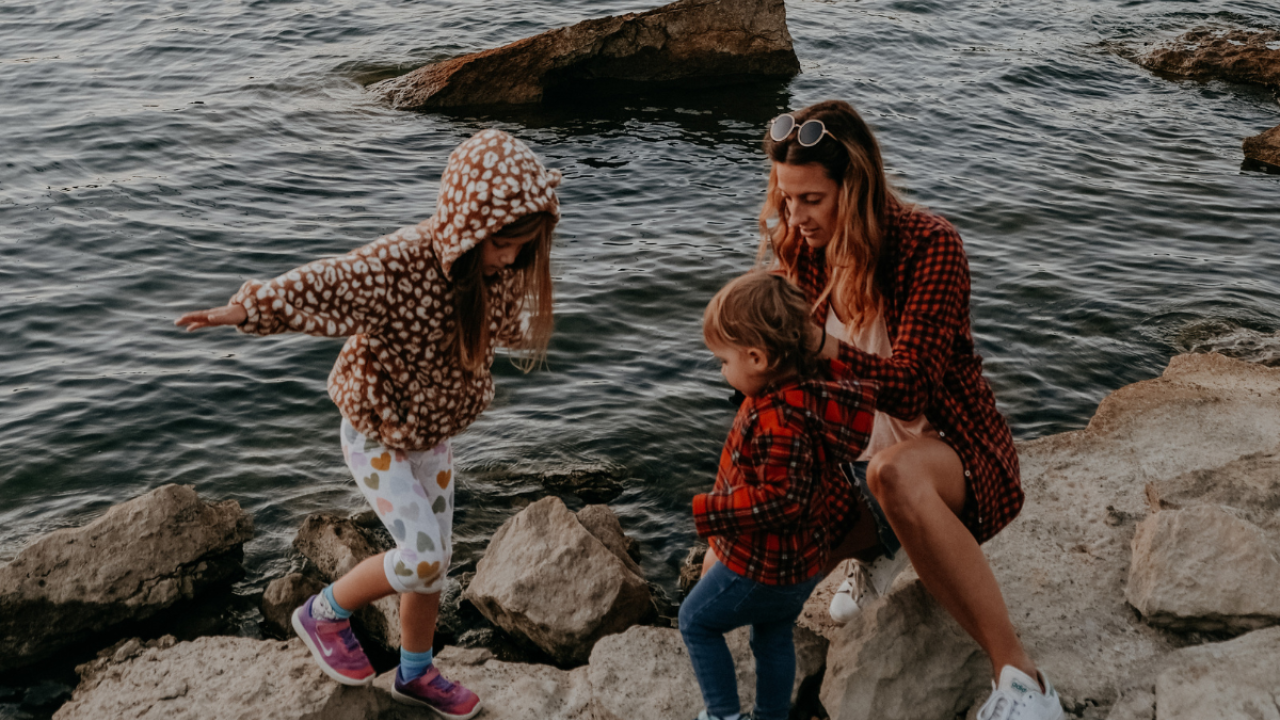 A family sits on rocks next to a lake during the fall.