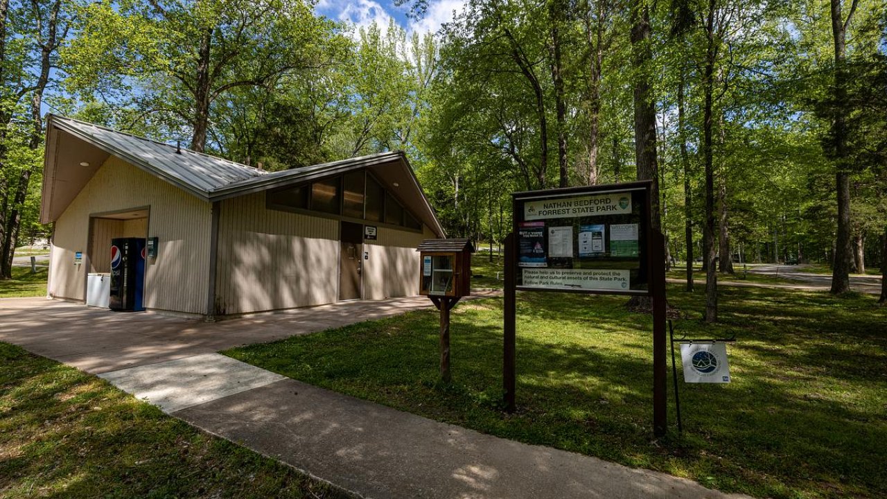 Modern park building surrounded by tall trees.