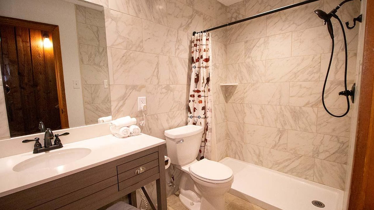Modern bathroom with marble walls, shower, sink, and toilet.