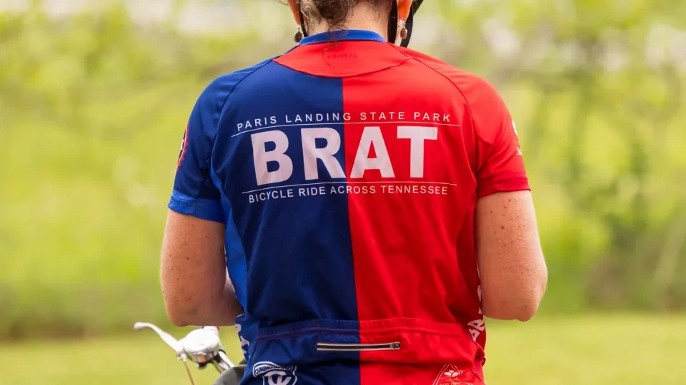 Cyclist in red and blue kit with helmet, outdoors.