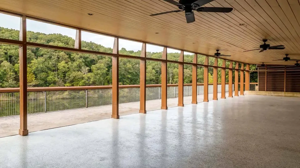 Outdoor pavilion with ceiling fans, overlooking a lush green forest.