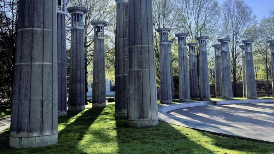 Tall stone columns encircle part of the Court of 3 Stars, casting long shadows across the grass under a bright, clear sky.