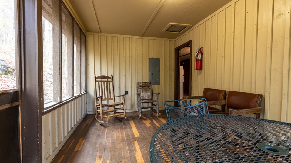 Breezeway on a sunny day with a rocking chair and a dining room table