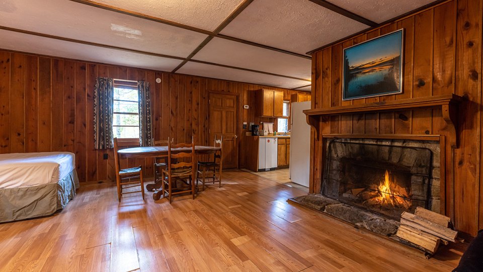 pretty fireplace inside cabin living room with dining room table and chairs 