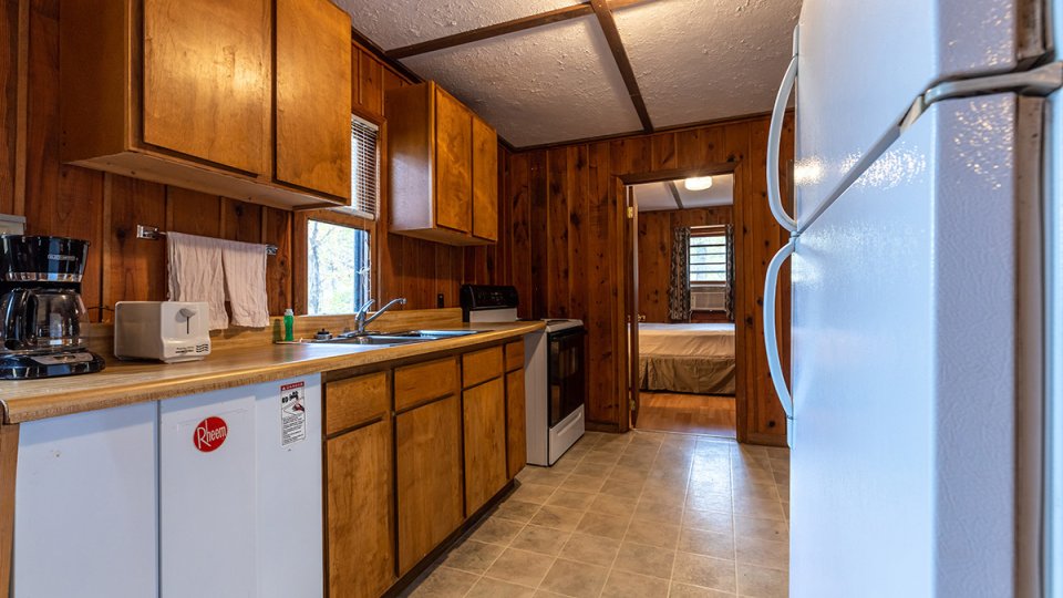 A small kitchen inside a cabin with a refrigerator and a oven