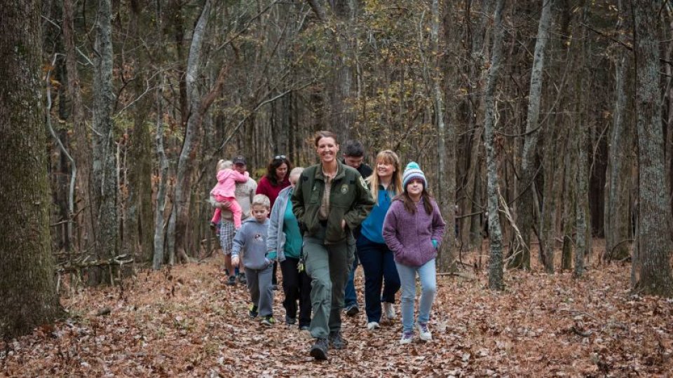 A group of parents and children hiking through trees. 