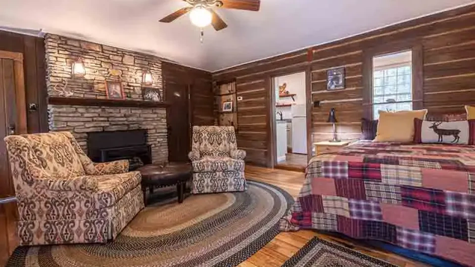 A furnished cabin bedroom with a neatly made bed and wooden furniture.