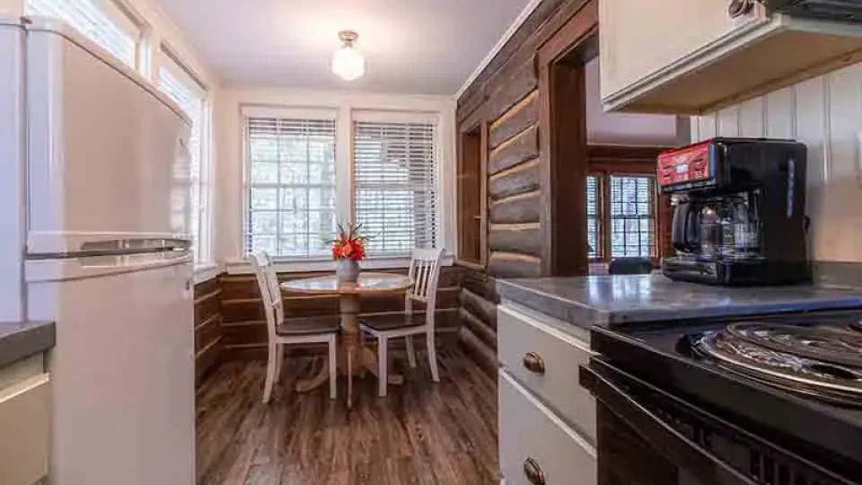 Rustic kitchen with a round table, chairs, and coffee maker.