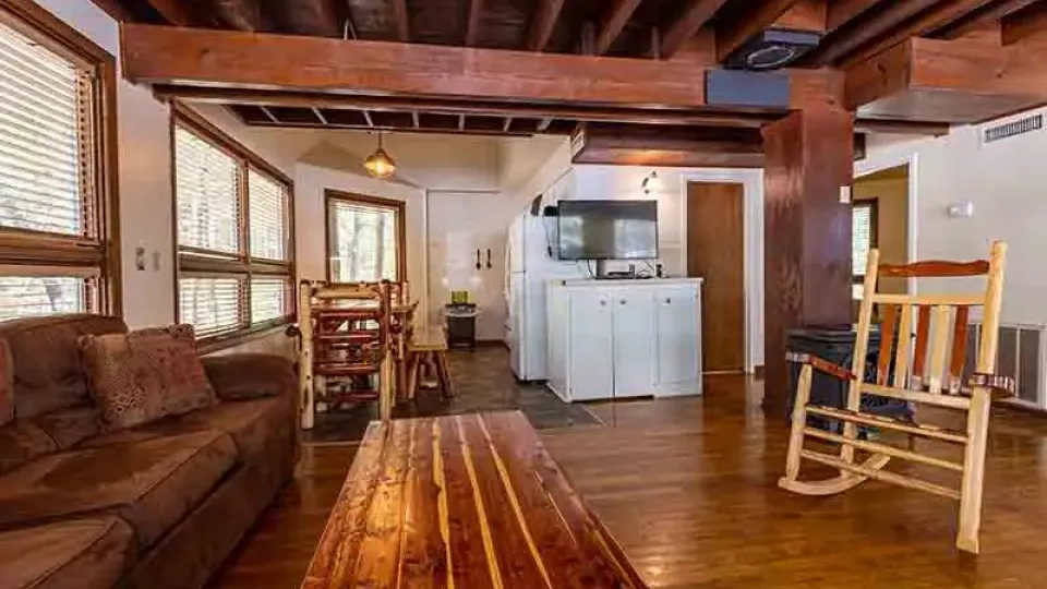 Another cabin living room with a coffee table and wood panel walls.