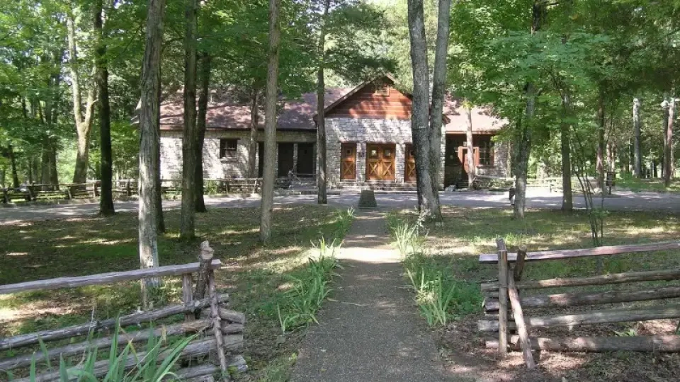 Cabin tucked back in the trees with a gravel walkway.