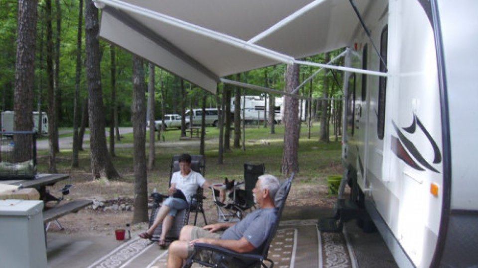 Two people sitting on chairs outside of a RV camping outside
