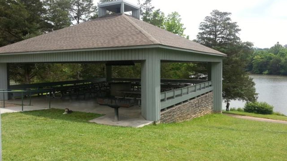 pavilion surrounded by grass, trees and lake