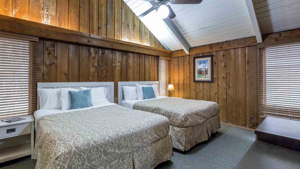 Wooden bedroom two beds, night stand, dresser, lamp, fan, overhead lighting, and windows