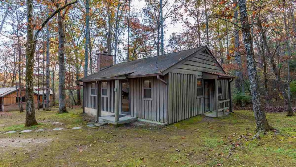 Wooden cabin surrounded by trees with stones leading to front door