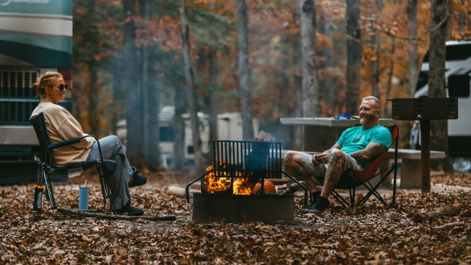 two man camping in the fall with a camp fire burning