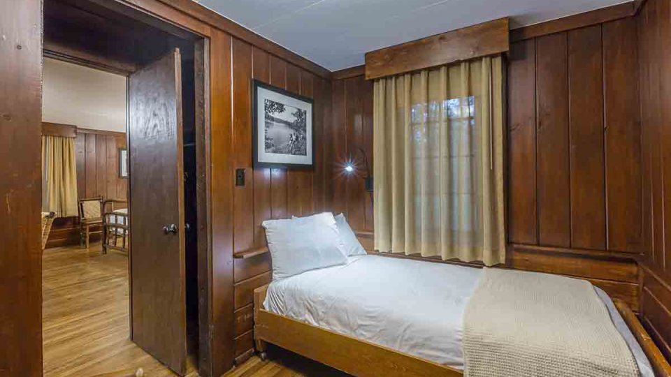 Wooden single bedroom with photo frame above bed and brown curtains