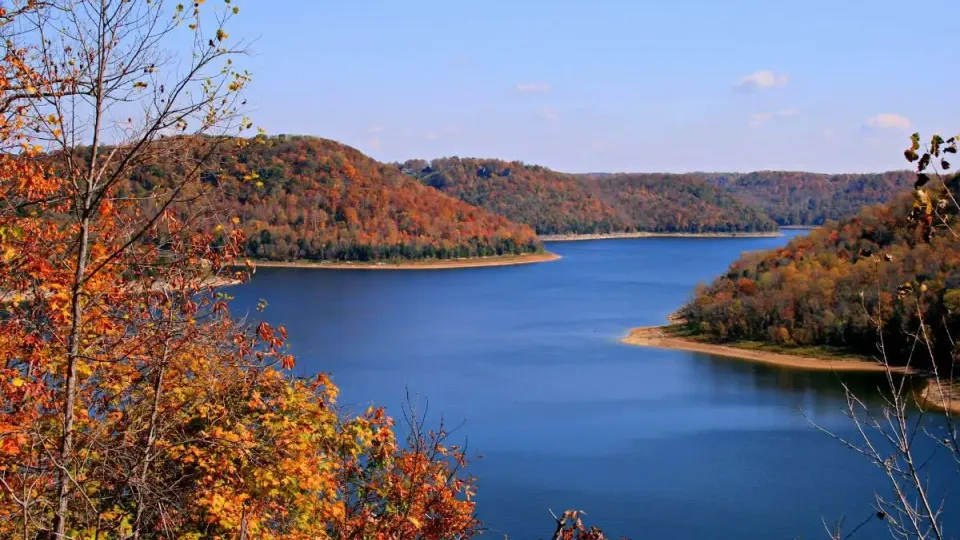 Scenic view of Center Hill Lake surrounded by forested hills in vibrant autumn colors under a clear blue sky.