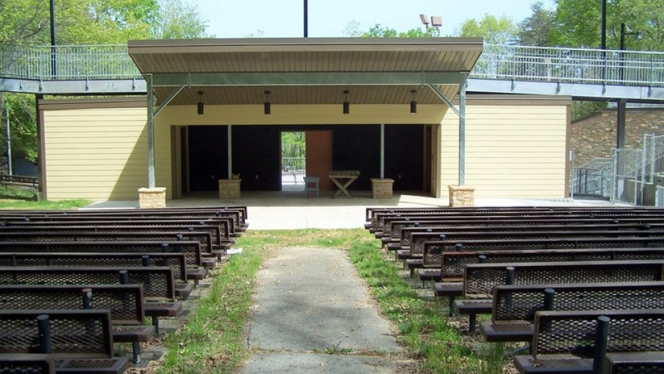Amphitheater with rows of empty metal benches facing the stage