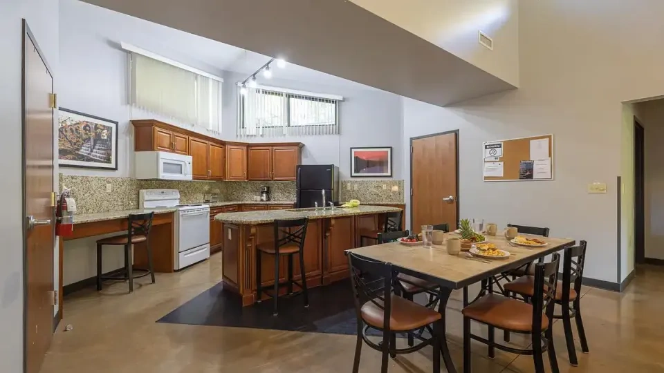 Modern kitchen and dining area with wood cabinets and granite countertops.