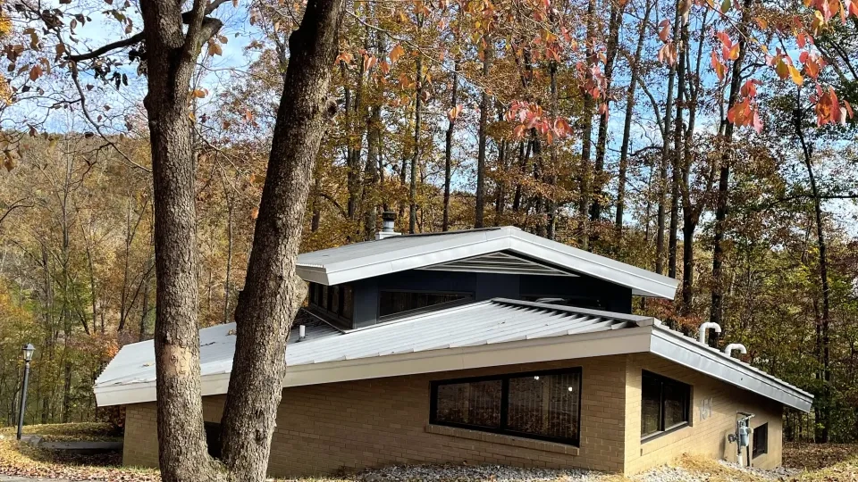 Modern house in autumn woods, surrounded by red and orange leaves.