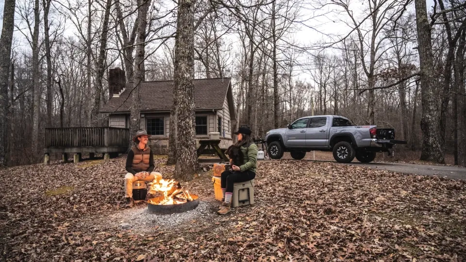 Rustic camping cabin at Natchez Trace with a porch and picnic table outside.