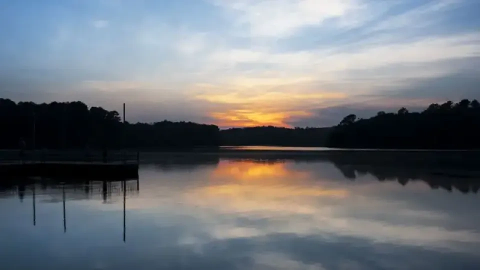 Sunset over the water with warm orange reflections.