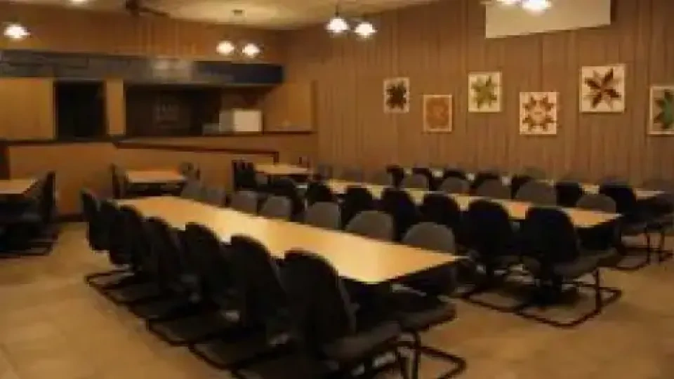 Large conference room with long tables, black chairs, and quilt art on walls.