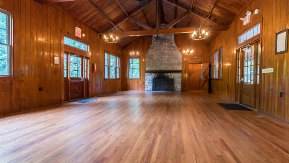 Wooden hall with stone fireplace and chandeliers.