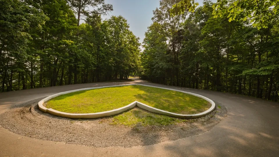 Heart-shaped grassy island in a forested roundabout.