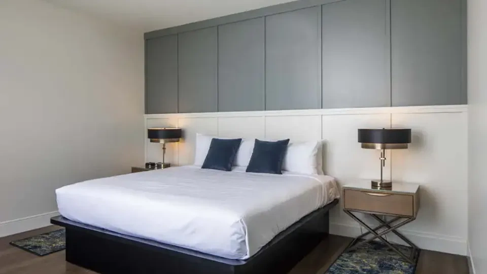 Modern bedroom with a large bed, blue pillows, and bedside lamps.