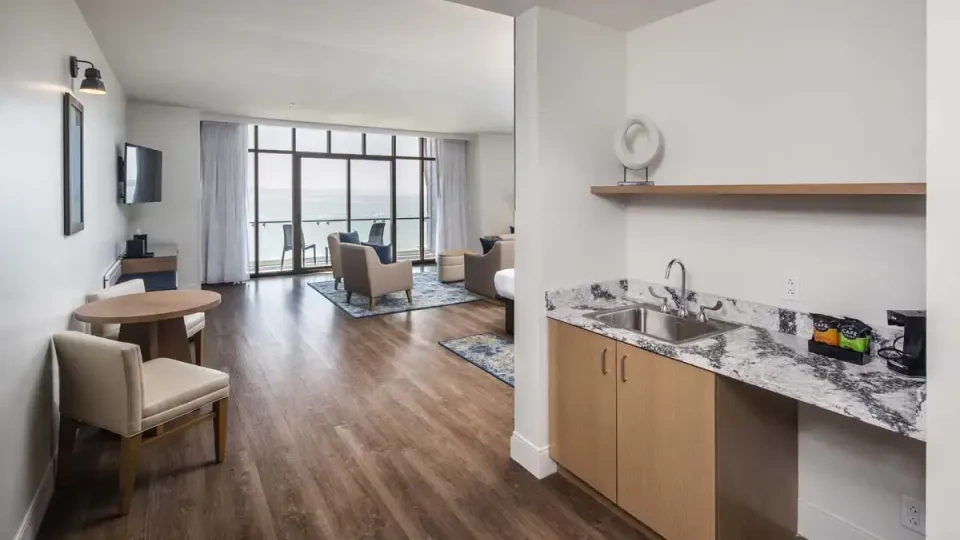 Spacious hotel suite with a kitchenette, seating area, and ocean view.