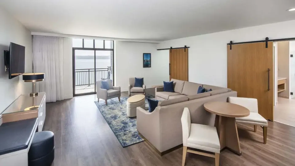 Spacious living room with a sofa, chairs, and a view of a lake through sliding doors.