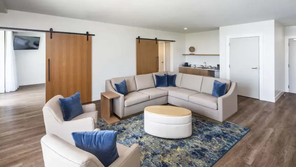 Modern living room with beige sectional, blue accents, and sliding wooden doors.